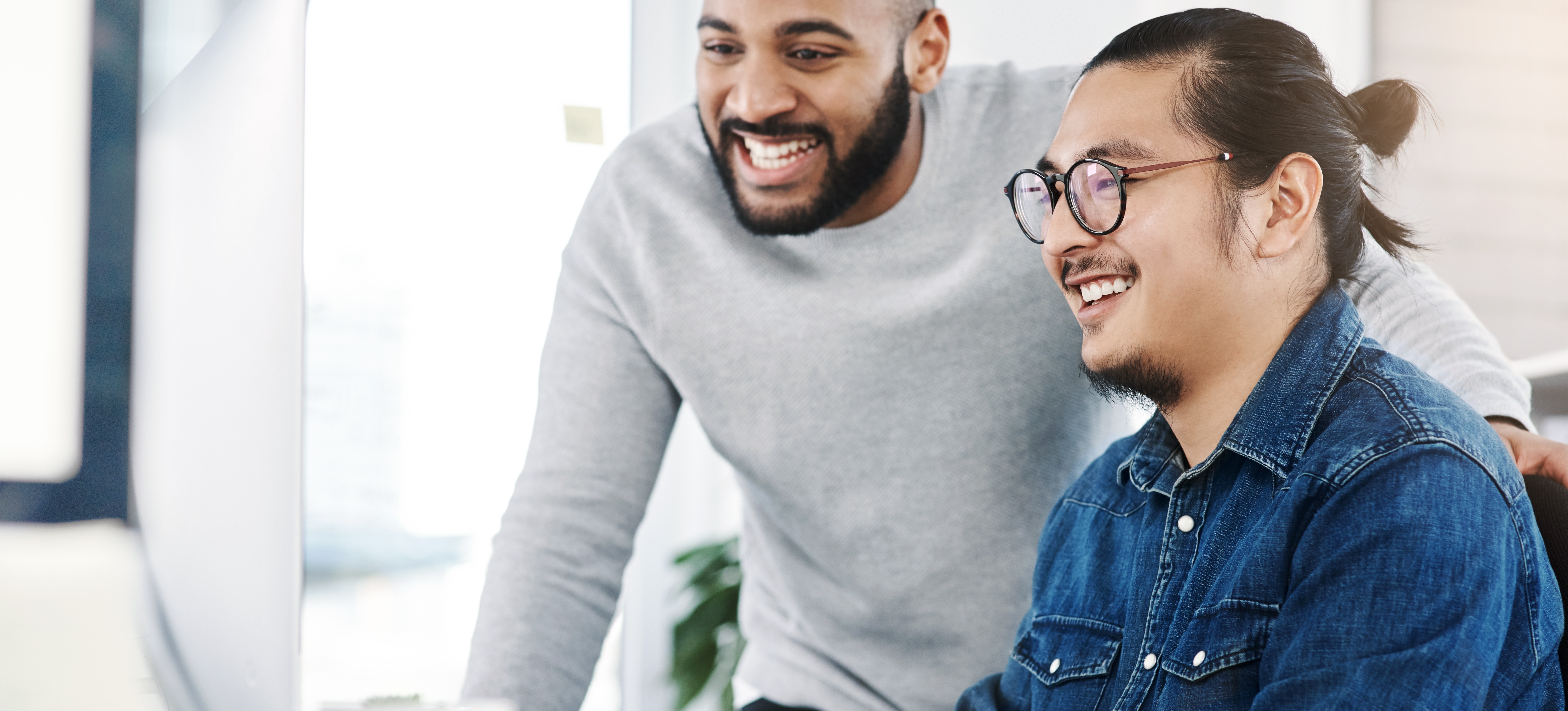 [Featured Image] Two computer programmers sit at a laptop and discuss what is open source software.   