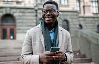 [Featuerd image] An aspiring business school student checks his GMAT score on his phone outside a university building.