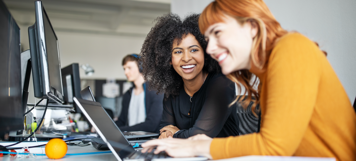 [Featured image] Two game developers working at a computer station.
