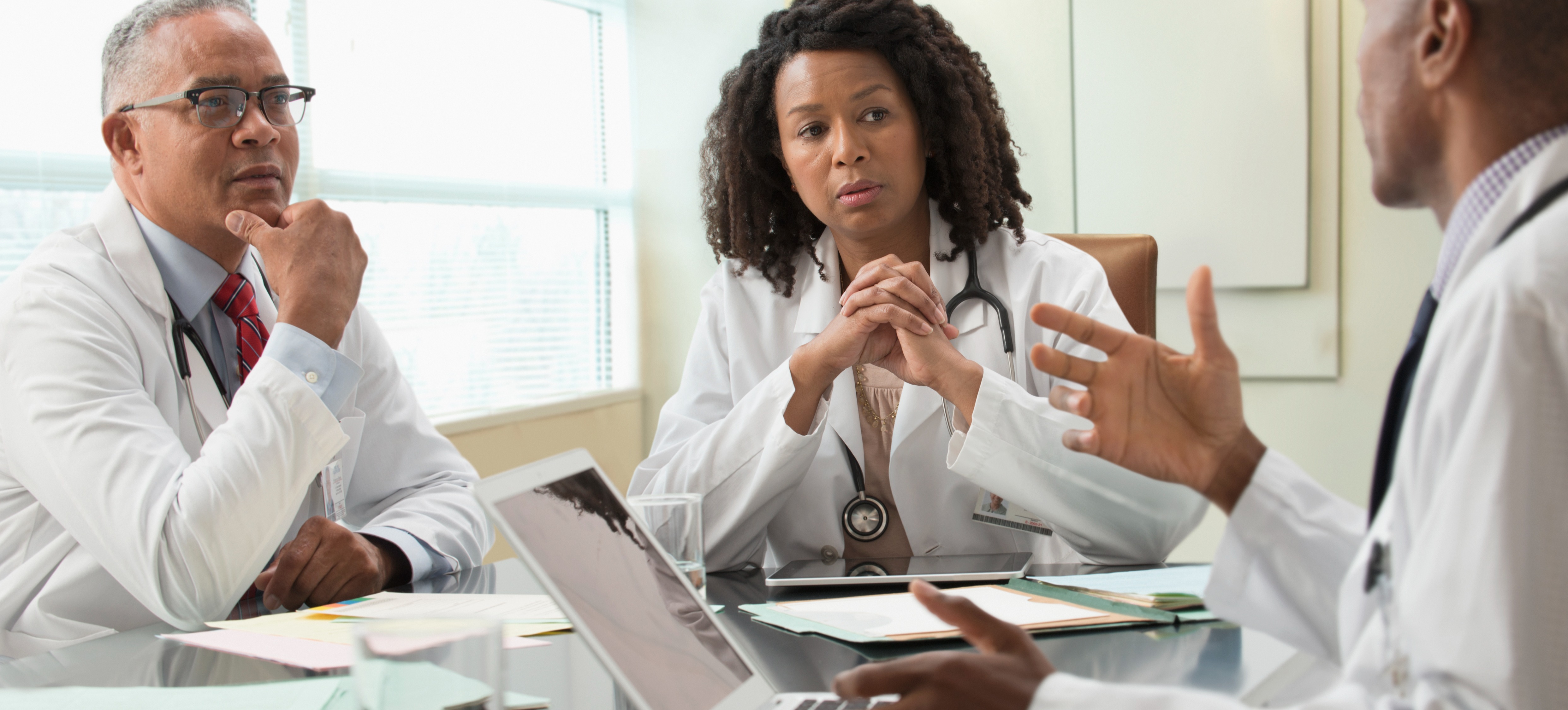 [Featured image] A group of doctors meets in a conference room to discuss how anomaly detection in machine learning can help them detect diseases in patients.  