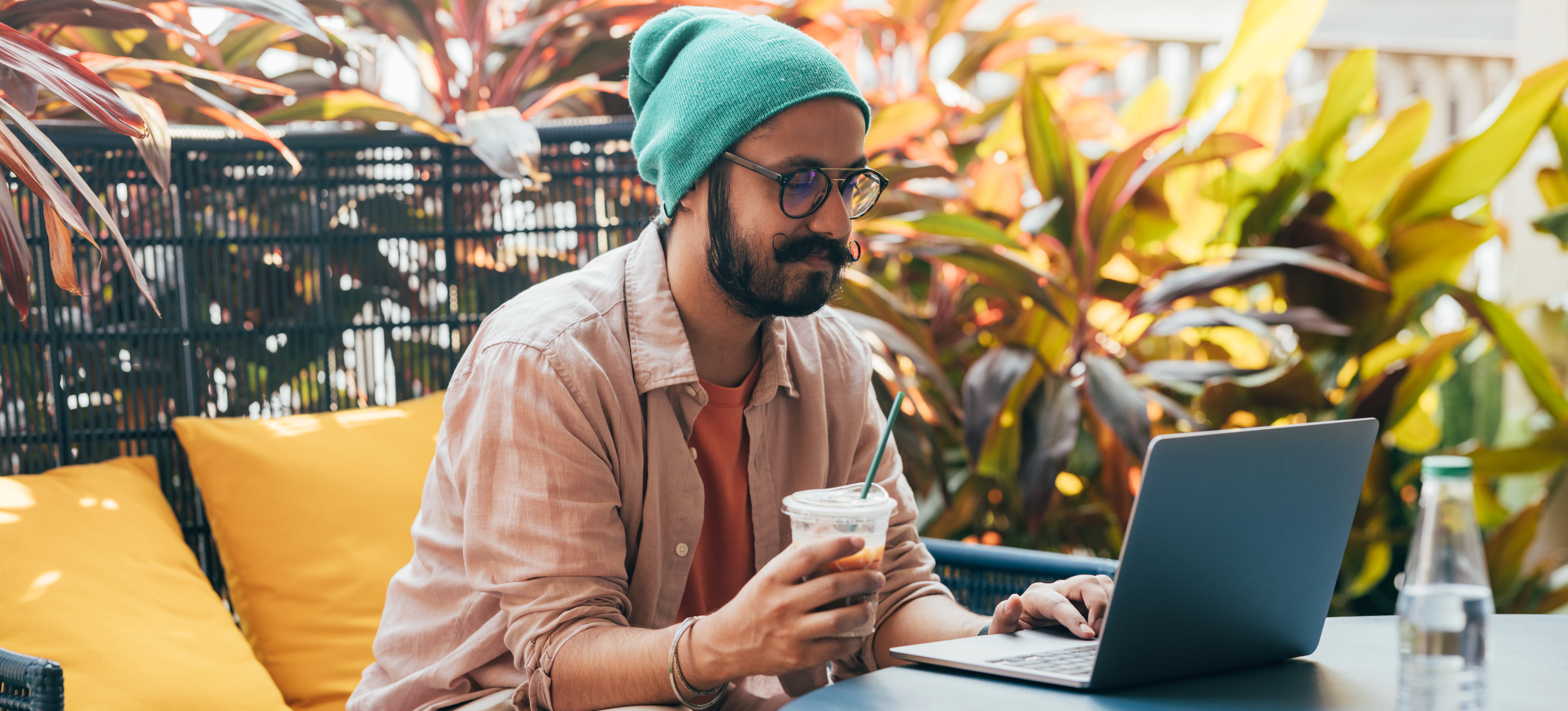 [Featured Image] A learner researches how to create a custom GPT on their laptop while drinking coffee in an outdoor setting.
