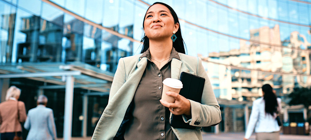 [Featured Image] A person carries their coffee as they confidently walk to a job interview for the next stage of their career path. 
