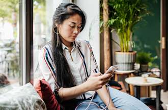 [Featured Image] A woman uses her mobile phone in a coffee shop.