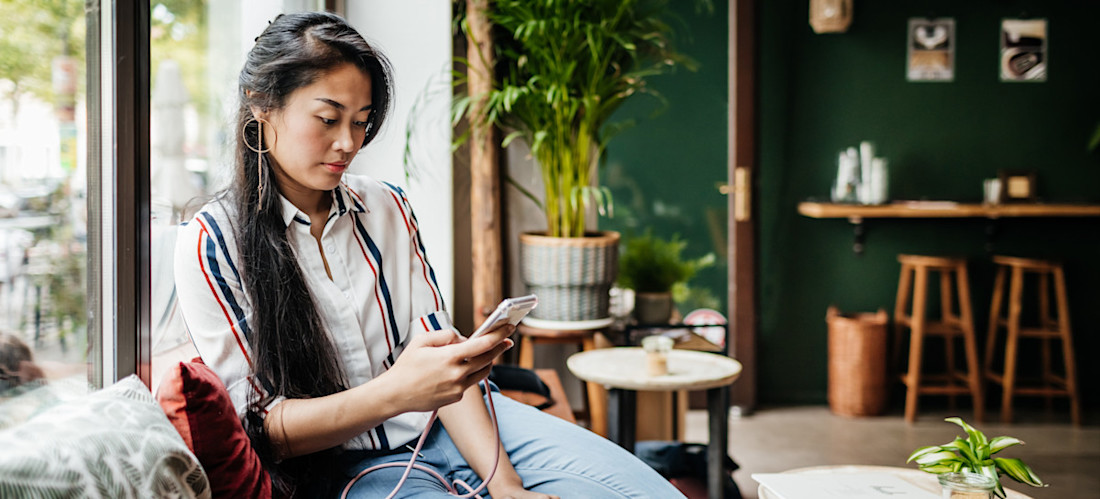 [Featured Image] A woman uses her mobile phone in a coffee shop.