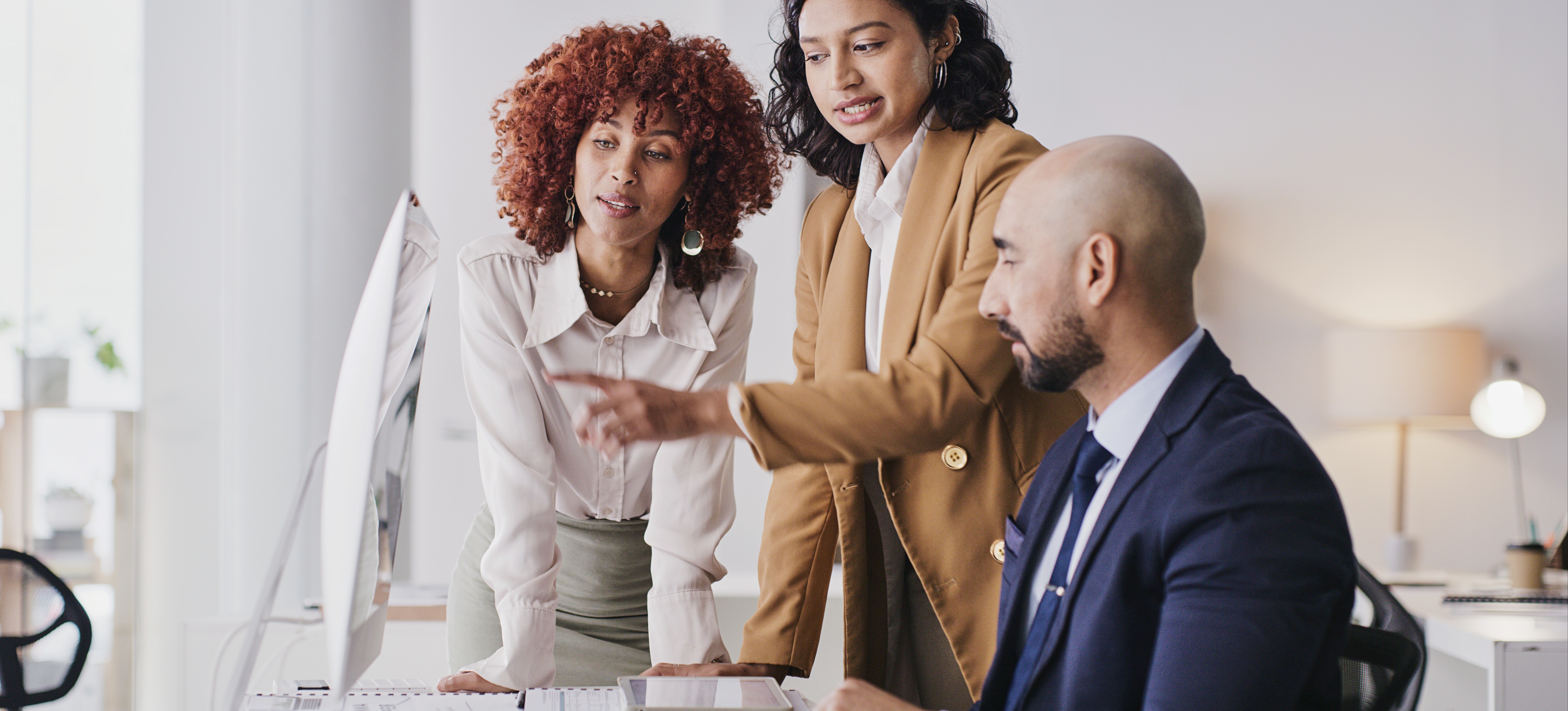 [Featured Image] Three colleagues are looking at a computer, discussing the characteristics of cloud computing.