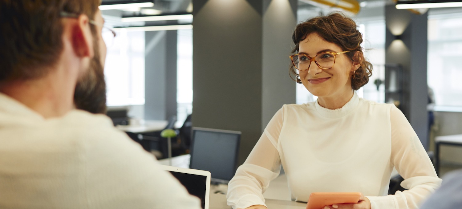 [Featured image] A young person with glasses interviews with a worker sitting across the table. 