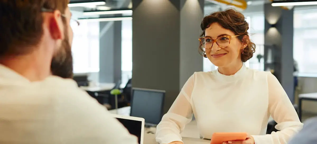 [Featured image] A young person with glasses interviews with a worker sitting across the table. 