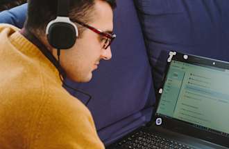 [Featured Image] A data scientist in a yellow sweater wears headphones and works on a laptop.