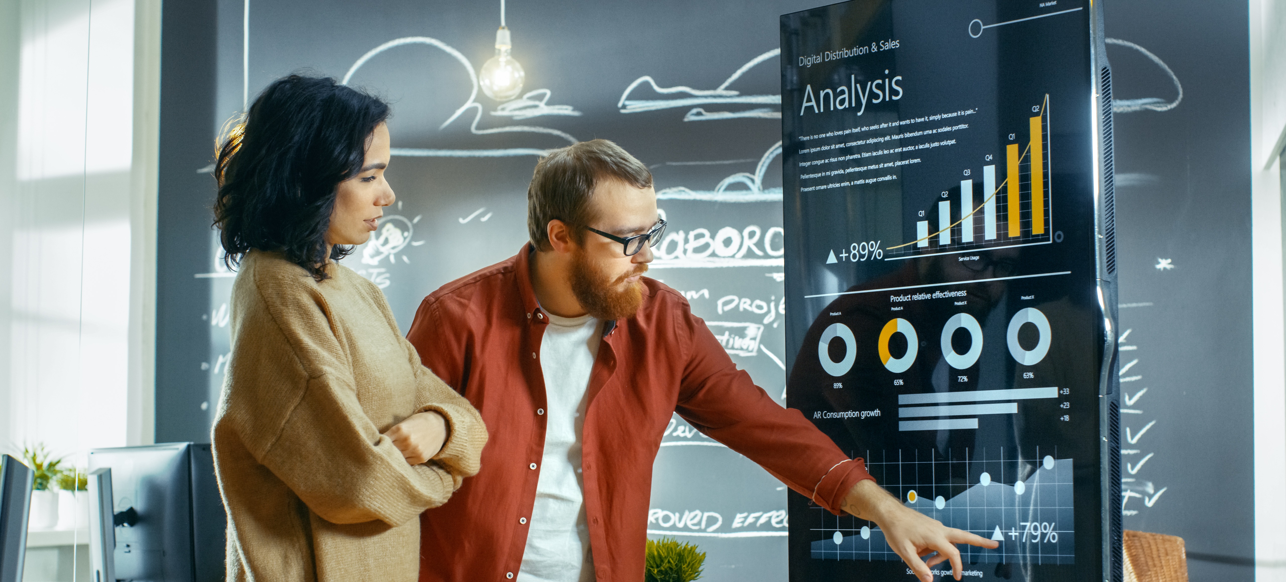 [Featured Image]:  A male and a female analyzing statistics from a series of tables and graphs. 