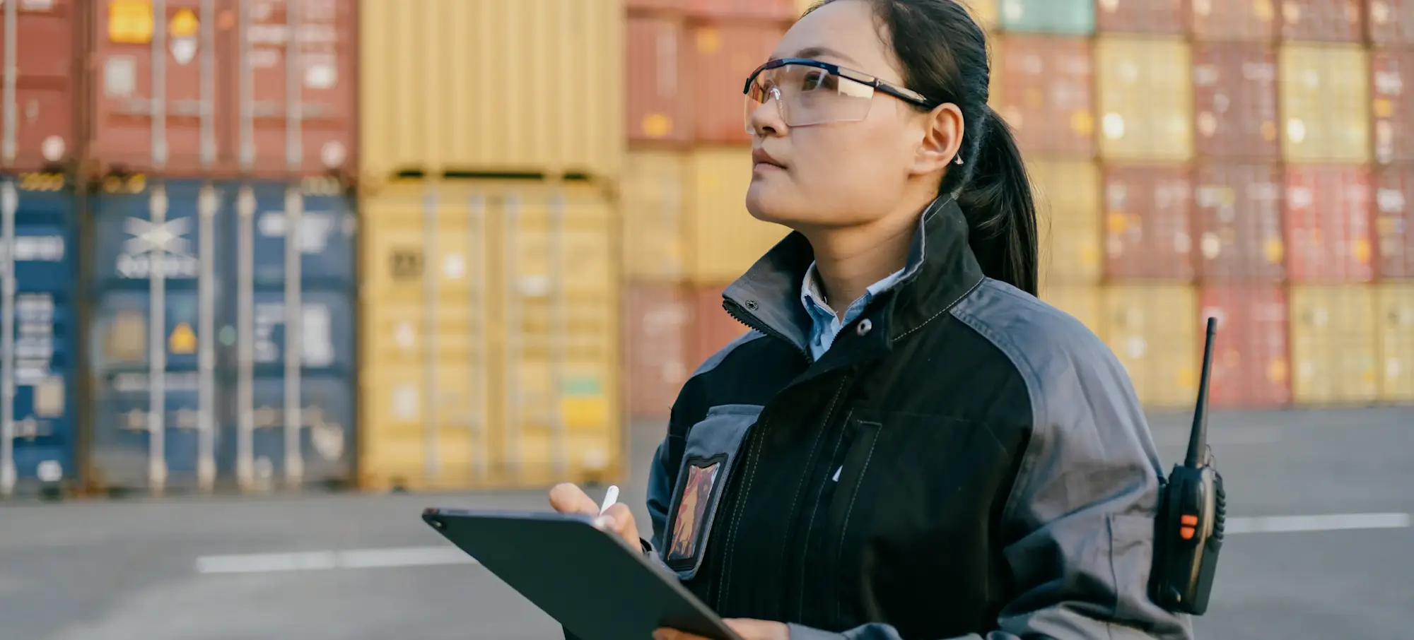 [Featured Image] A logistics specialist checks their tablet at a container terminal.