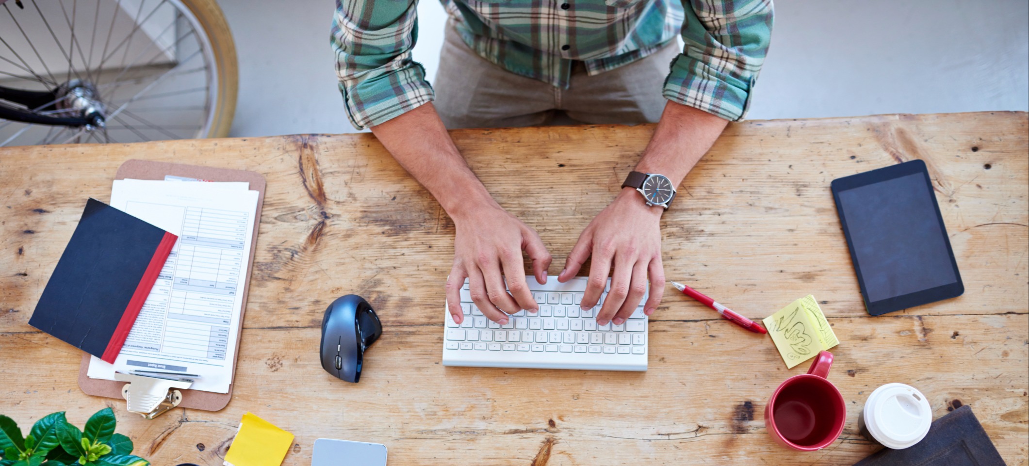 [Hauptbild] Eine Person sitzt an einem Tisch mit Arbeitsaufgaben und tippt auf einer Tastatur mit einer OpenAI-App.