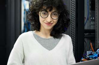 [Featured image] A member of the IT staff wears black glasses and a white sweater and checks the security of servers with their laptop.