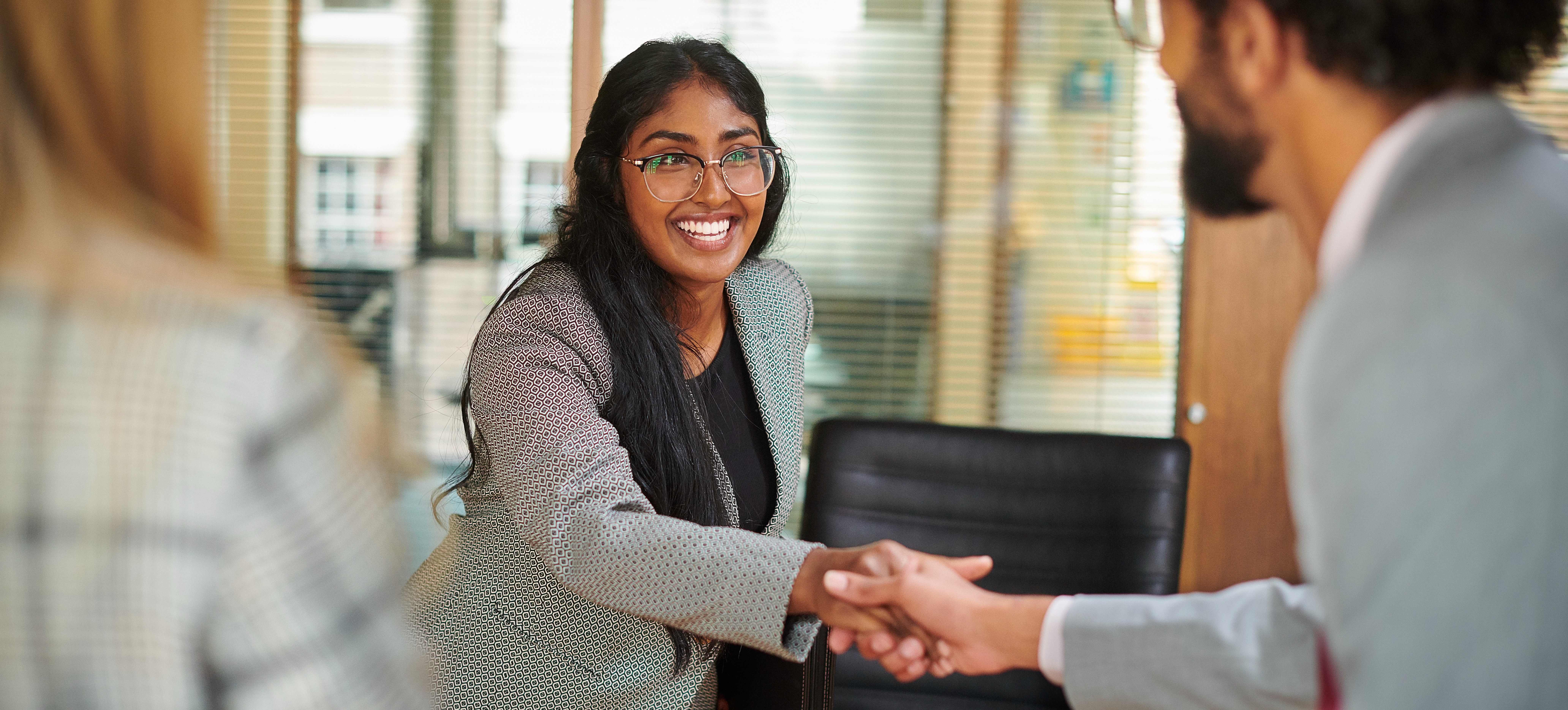[Featured image]: A person greets a potential employee with a handshake and uses their recruiter skills to build rapport.

