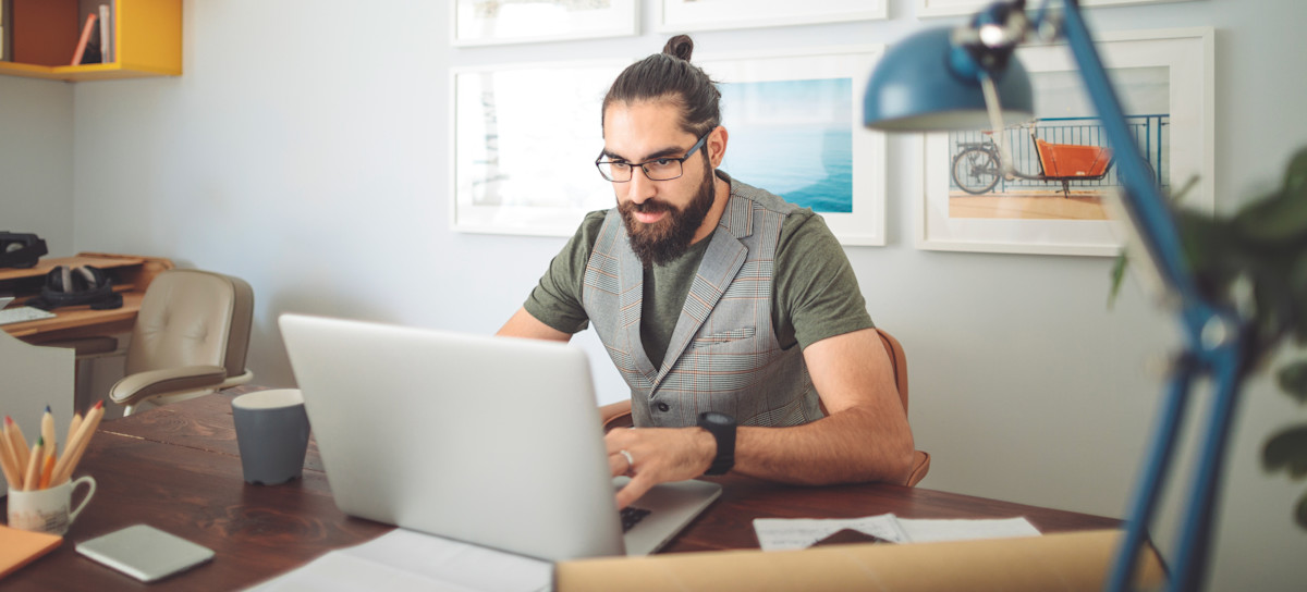 [Featured Image] A person works at their desk, typing on their laptop and learning about digital skills.