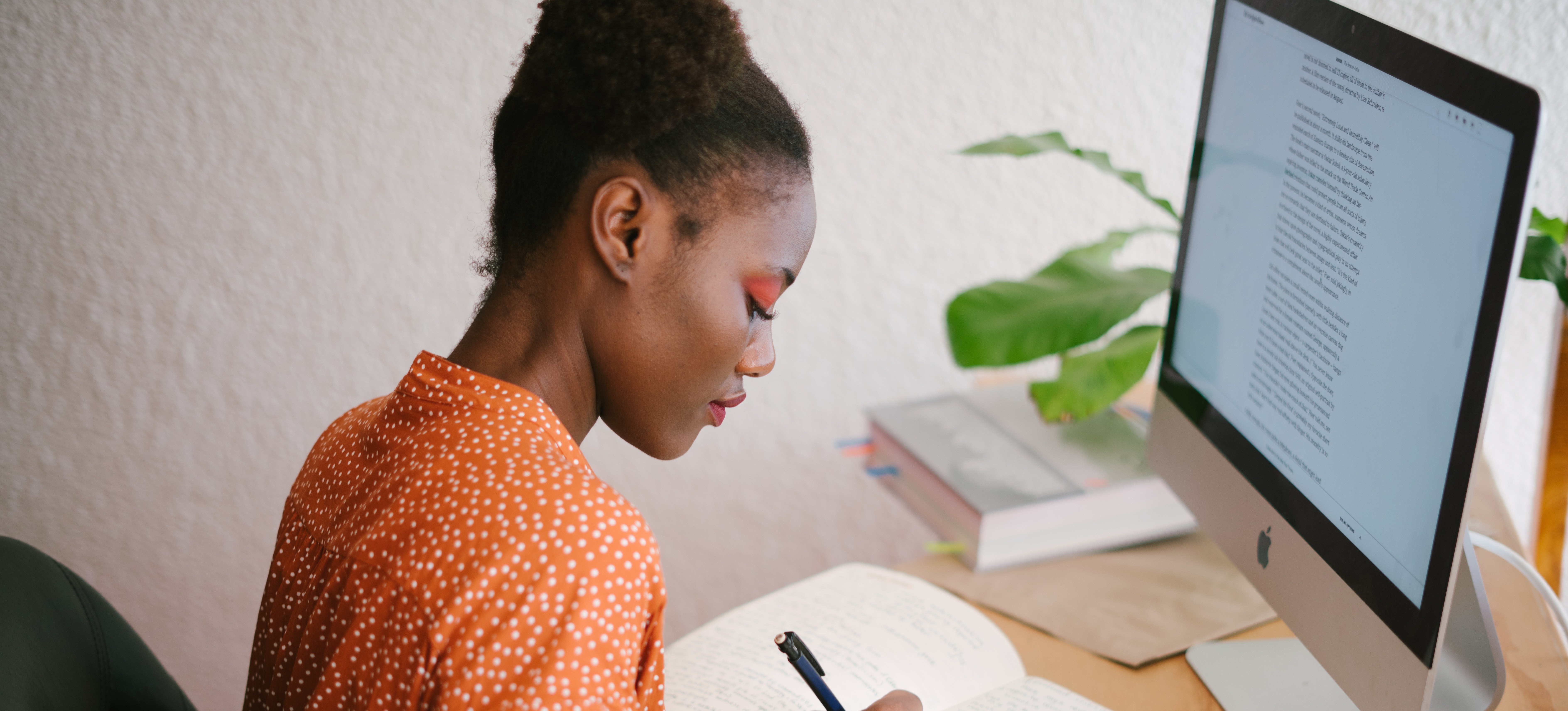 [Image en vedette] : Un associé informatique portant un haut orange est assis devant un ordinateur de bureau, explorant des informations sur les certifications informatiques gratuites.