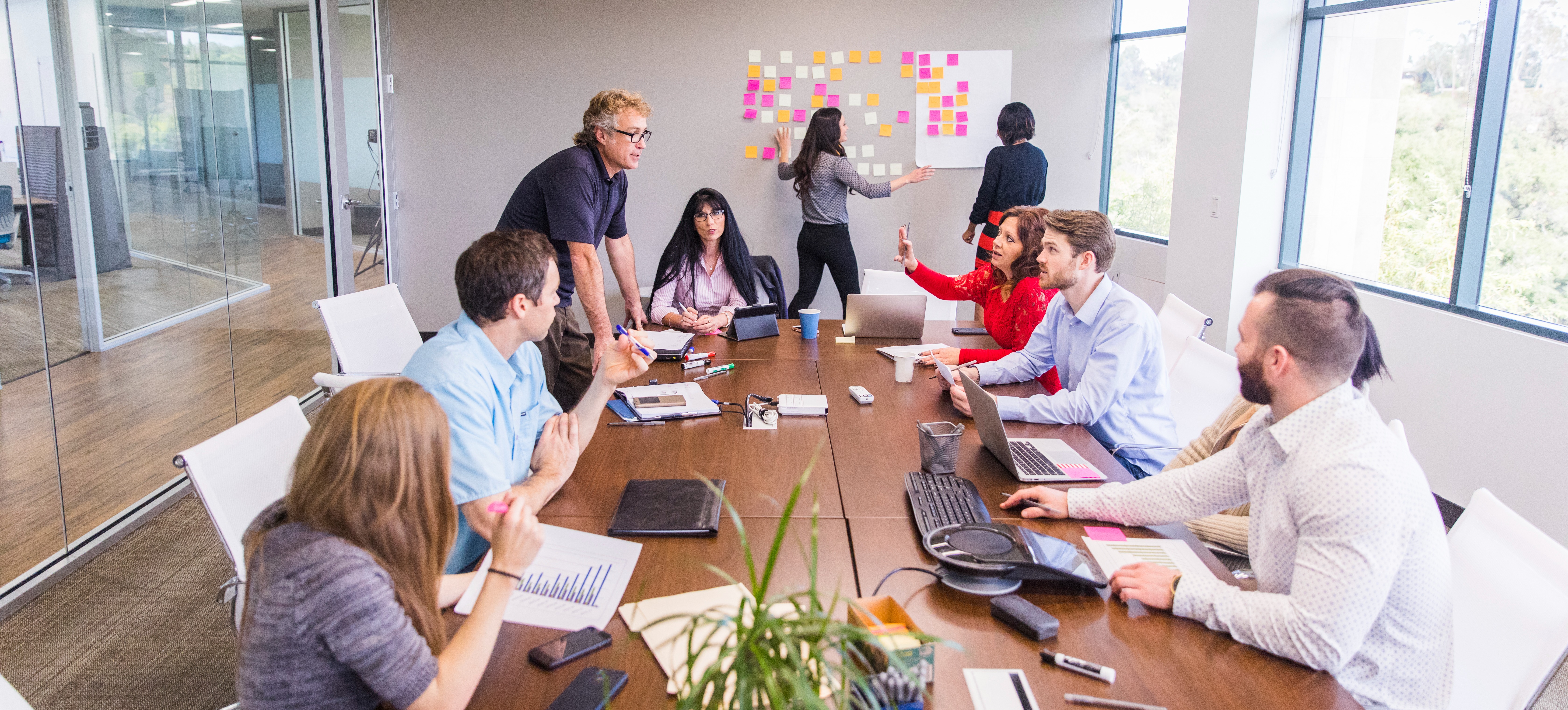 [Featured Image] A business team at a conference table in an office discusses what is a project scope in determining how they can help their clients.

