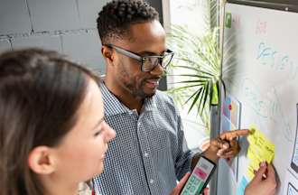 [Featured Image] Two React Native developers plan a project on a whiteboard.