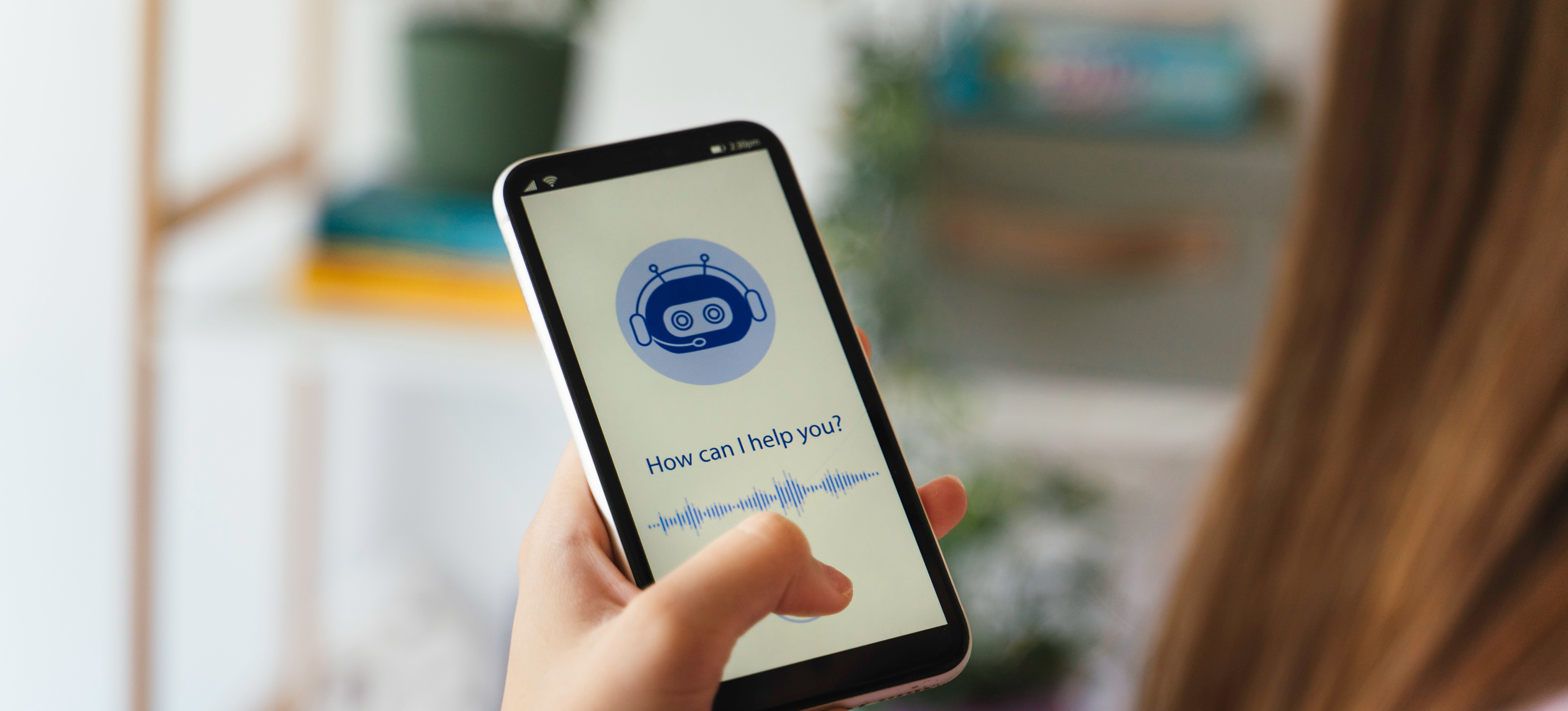 [Featured Image] Chatbot marketing is featured on a smartphone as a person holds the phone and speaks to a chatbot.
