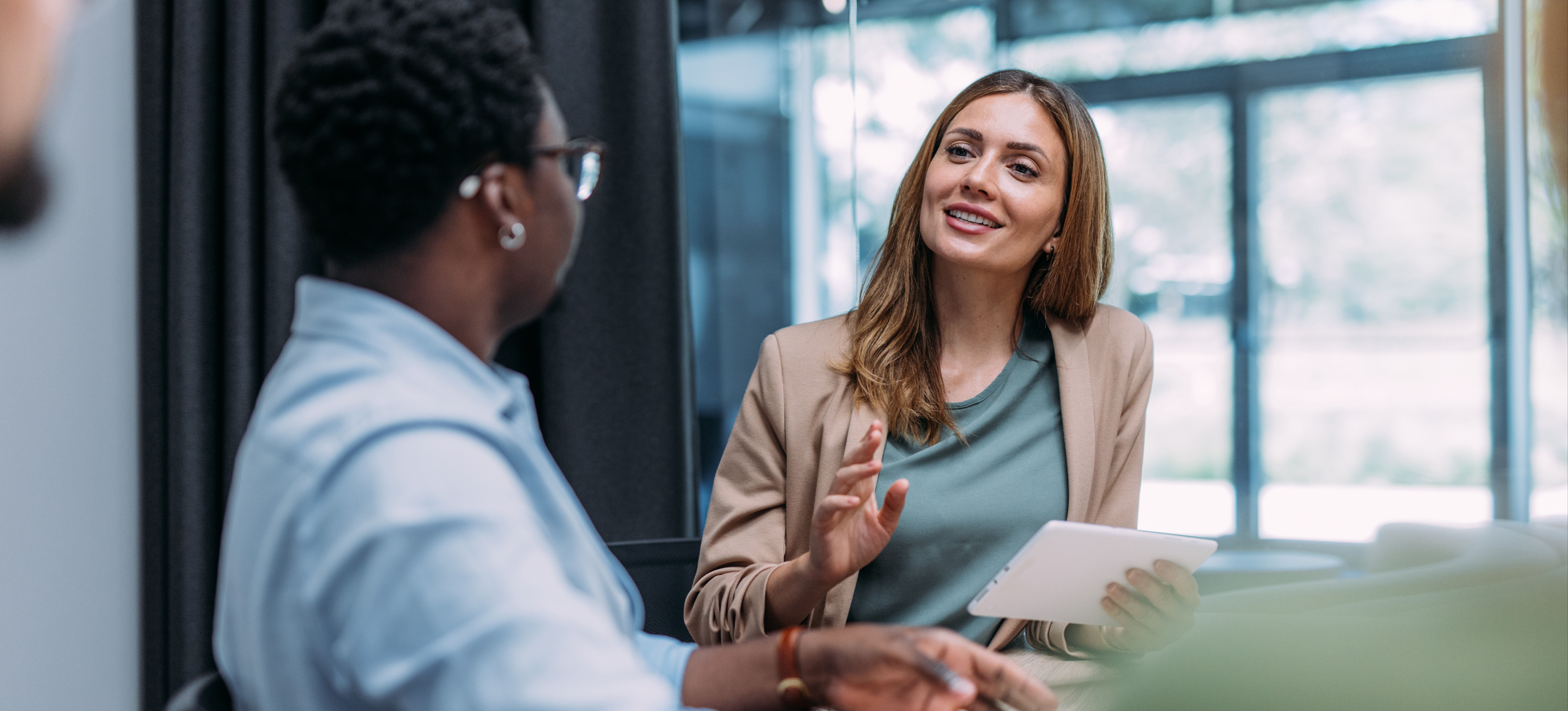 [Hauptbild] Ein Personalverantwortlicher übt effektive Führungsqualitäten aus, indem er freundlich mit einem Mitarbeiter spricht, während beide in einem gut beleuchteten Büro sitzen.