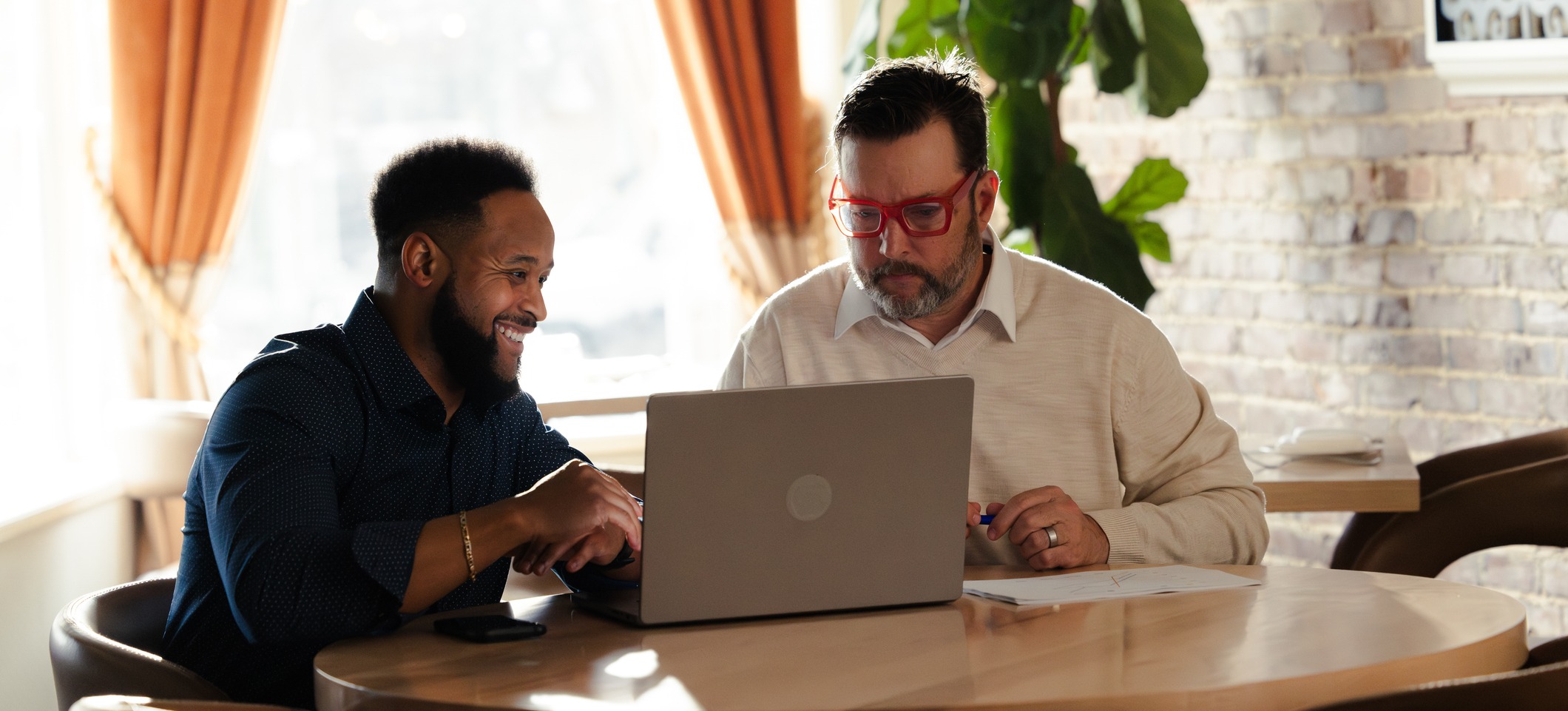 [Featured Image] A mentor shows a new employee how to use AI tools to improve data quality as part of their workflow. 

