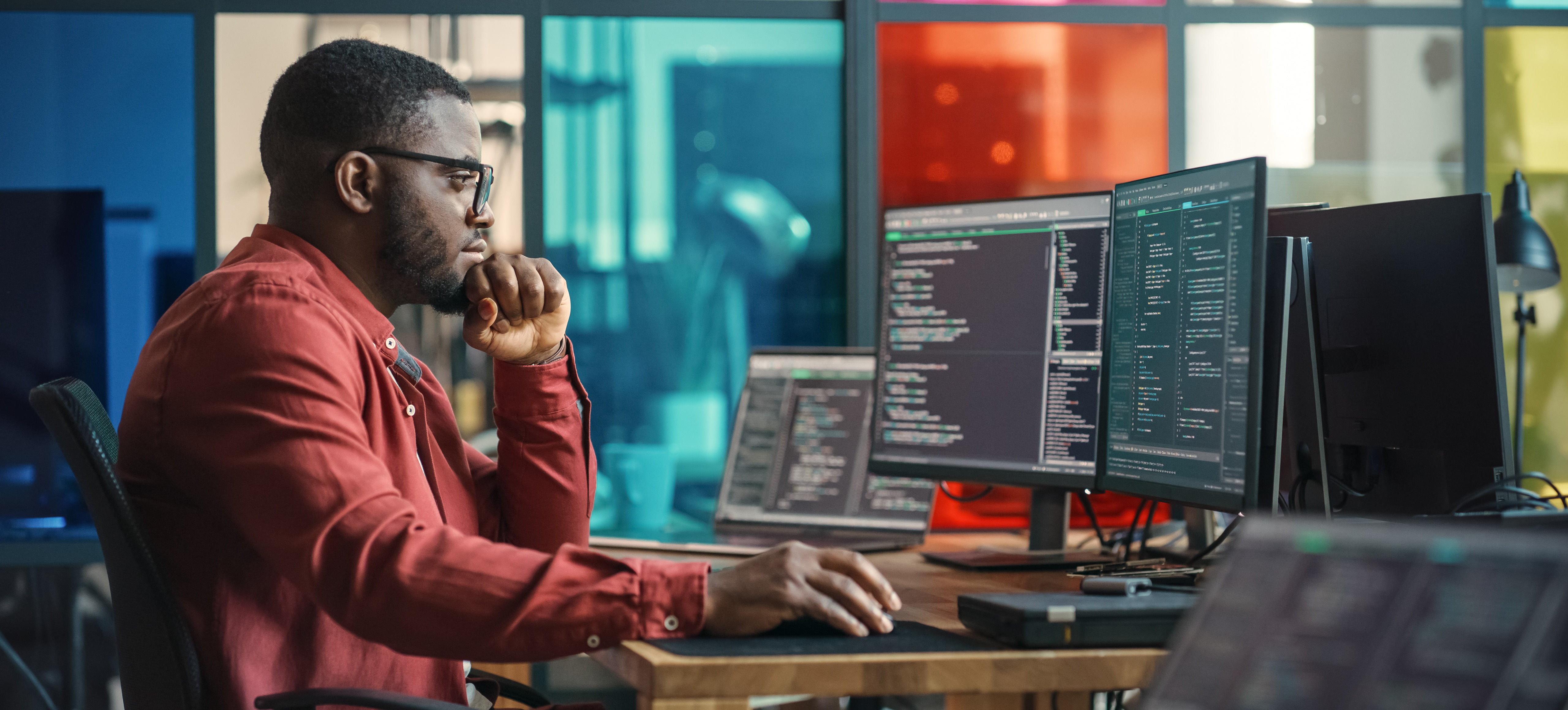 [Featured Image] An aspiring software developer studies some of the most popular programming languages on several computer screens.
