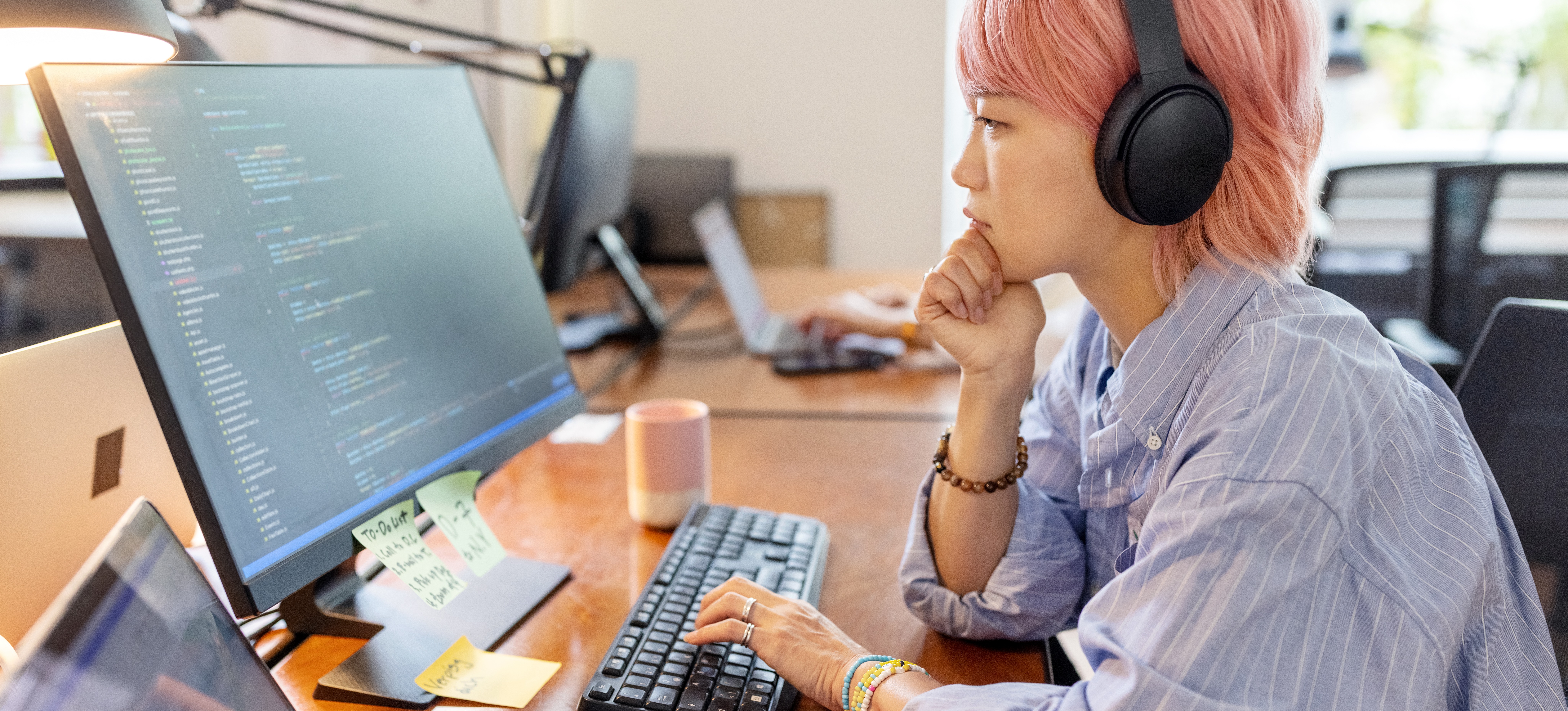 [Featured Image] A woman wears a headset and looks at a computer monitor, thinking while she deals with her team's technical debt.
