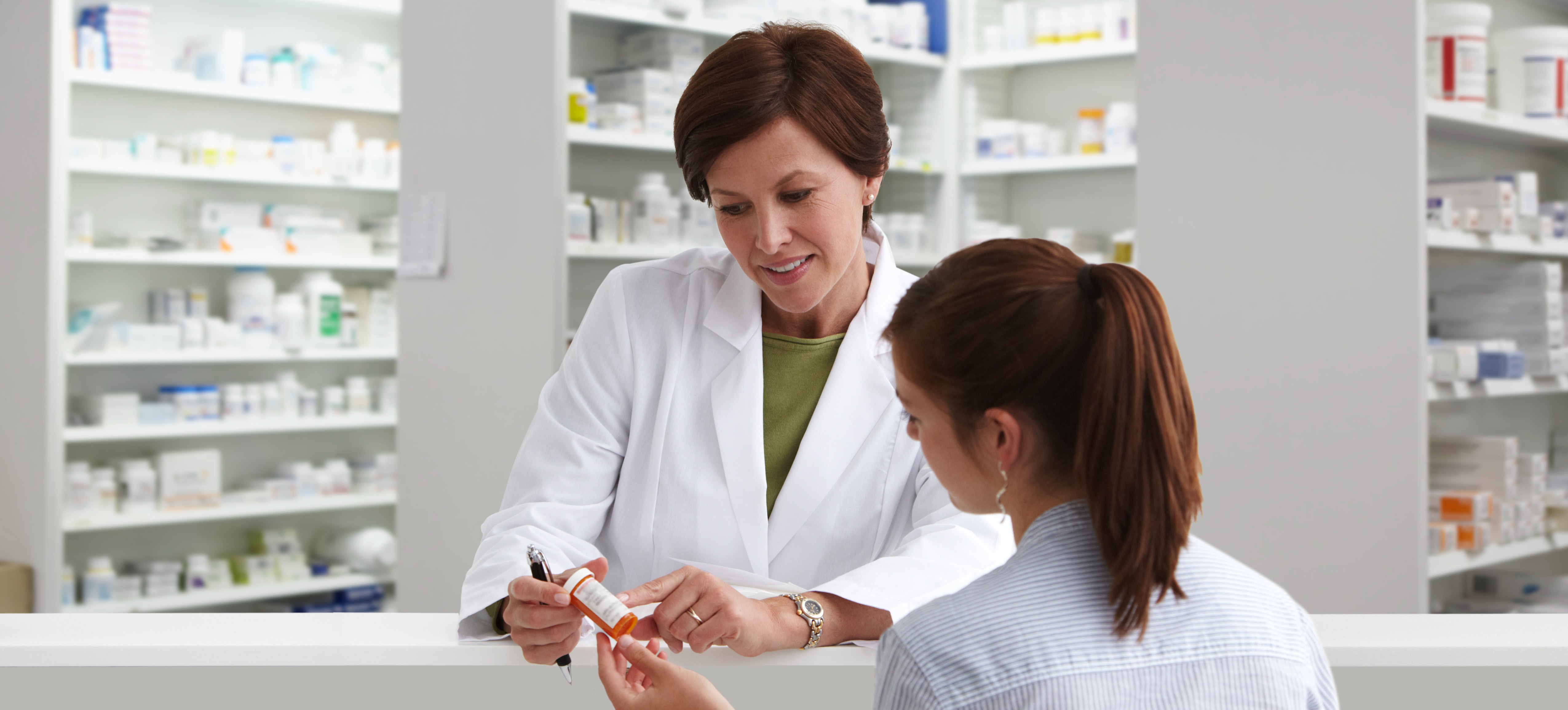 [Feature Image] A senior member of the pharmacy staff, who earns an above-average pharmacist salary, consults with a patient about their medication.
