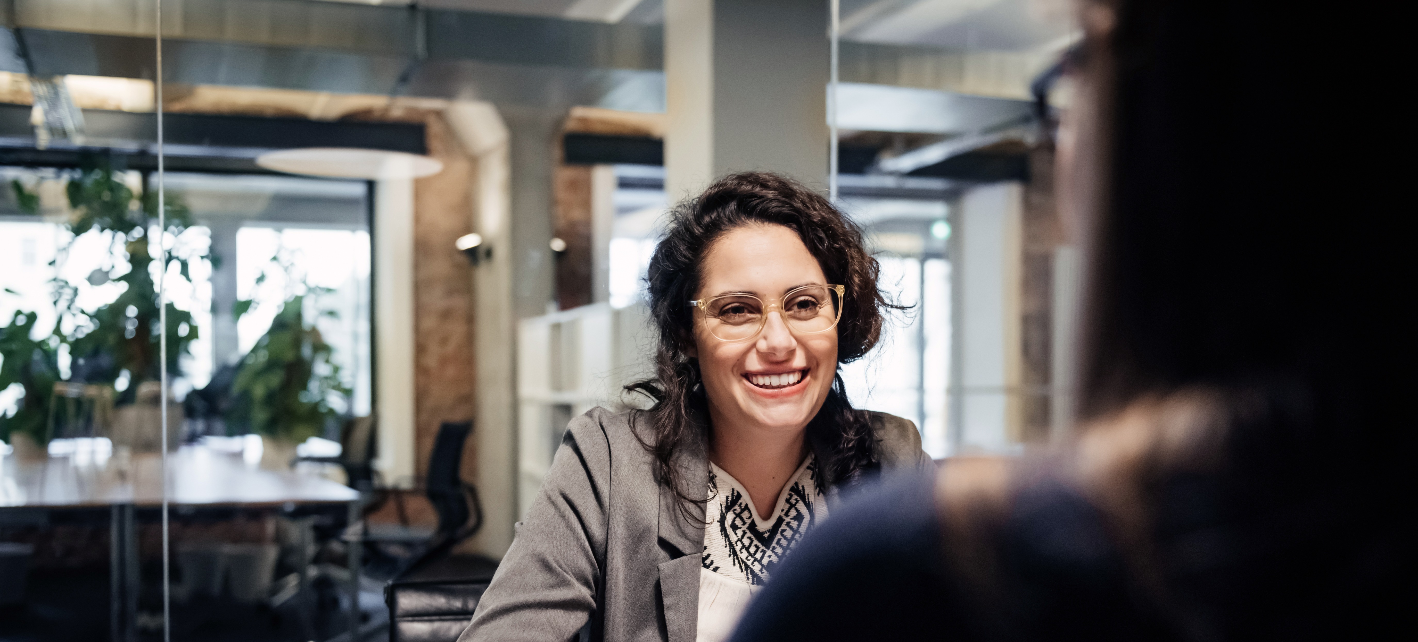 [Featured Image] A person in glasses and a gray jacket answers hr interview questions in an office. 