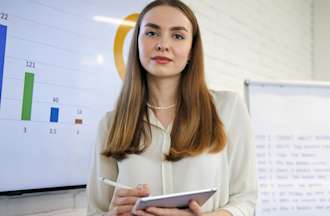 [Featured image] A business analyst stands in front of a screen showing a dashboard.