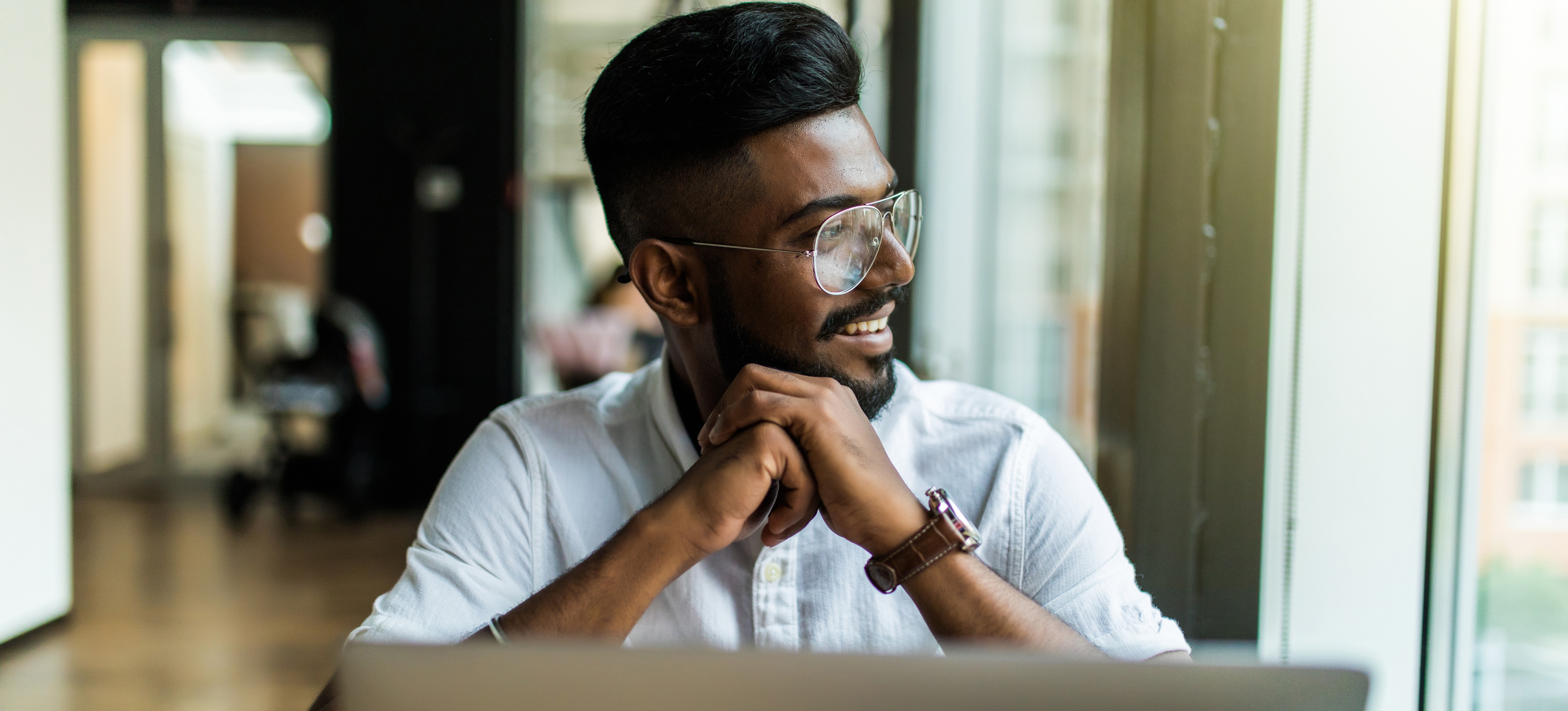 [Featured Image]: A man sits in front of a laptop contemplating the differences between IaaS, PaaS, and SaaS used in cloud computing.
