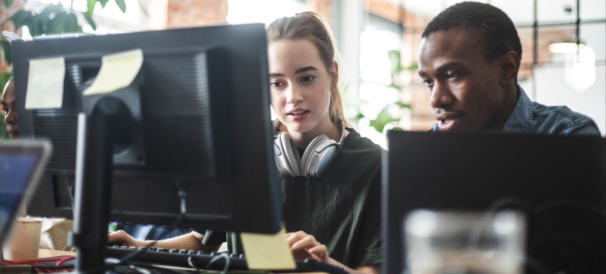 [Featured Image] Two friends work side by side at a desktop computer, researching how to get into cloud computing.