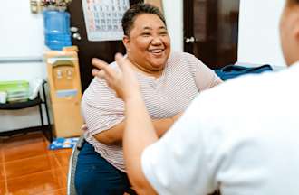 A smiling woman in a wheelchair interviews for a data analyst job with a hiring manager.