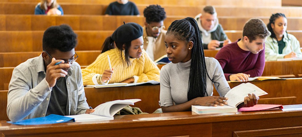 [Featured Image]: Students in a university classroom read notes and discuss topics such as what are college credits.
