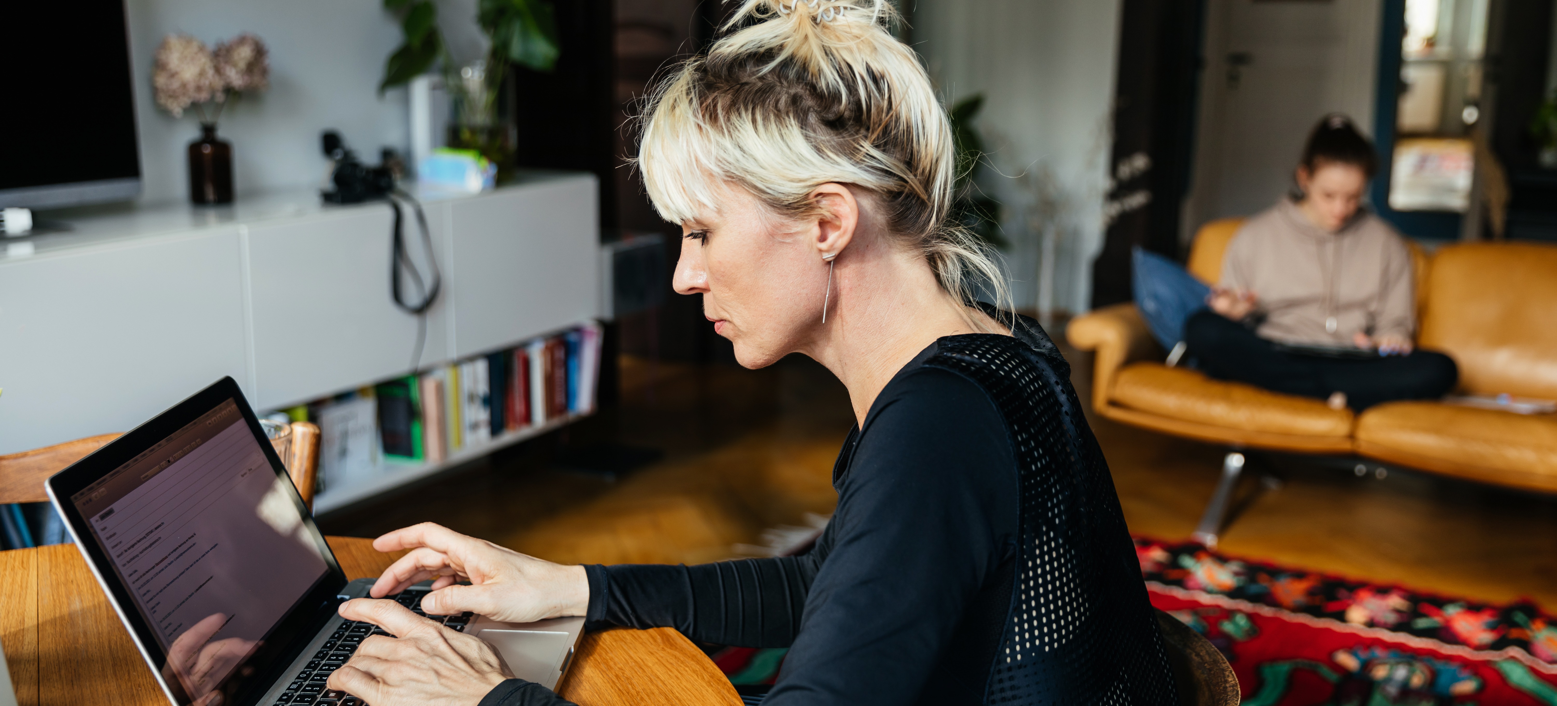 [Featured Image] A women working on her laptop at home, is sending a test email in mailchimp for a marketing project.