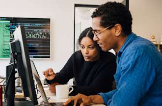 [Featured Image]: Two software engineers work on a desktop computer.