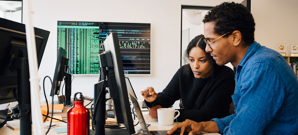 [Featured Image]: Two software engineers work on a desktop computer.