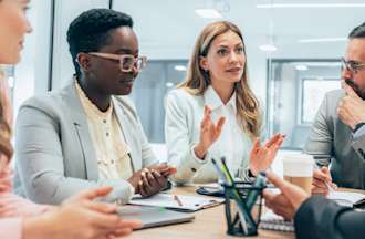 [Featured Image] A group of marketers practice data-driven decision making during a business meeting. 