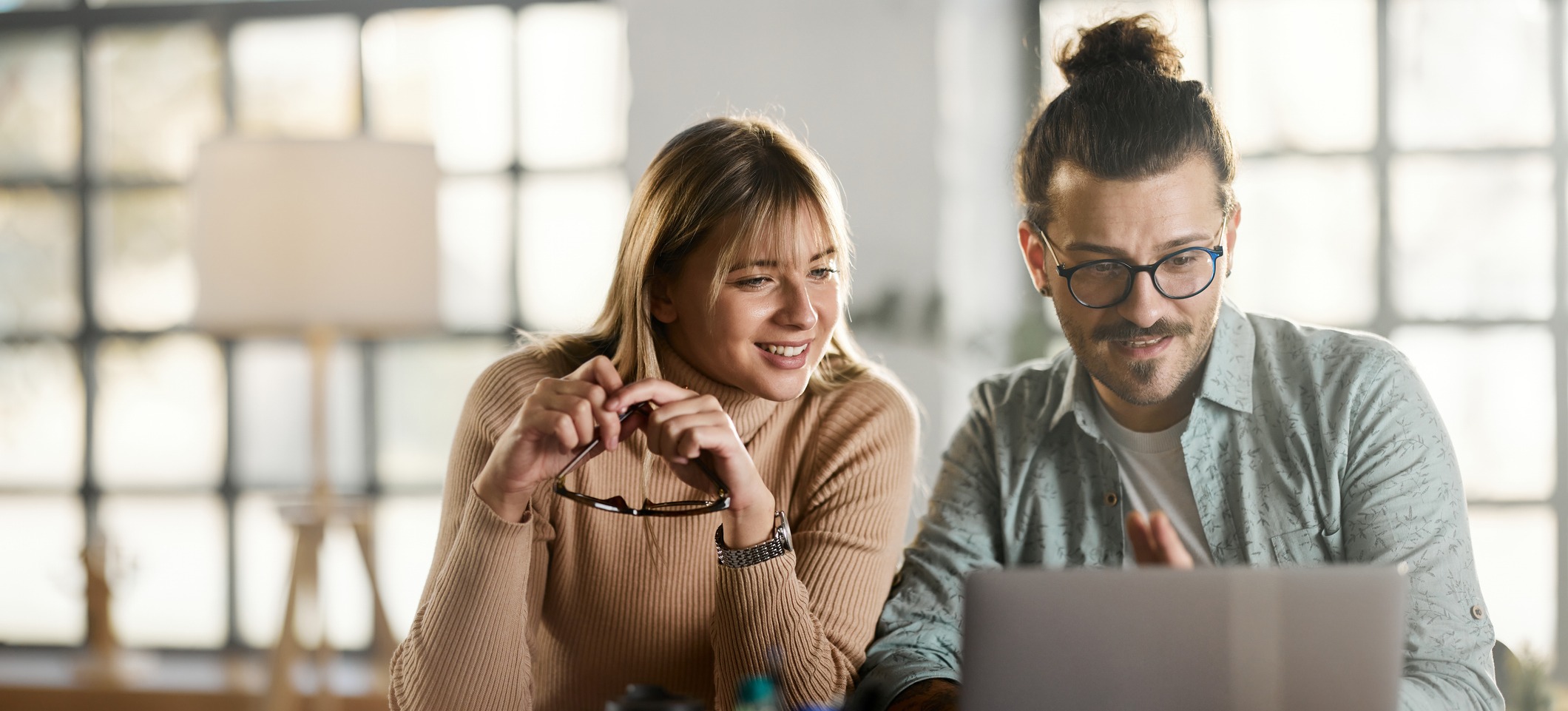 [Feature Image] Two marketing professionals research best practices and use cases of machine learning in marketing as they seek to optimize their campaigns.
