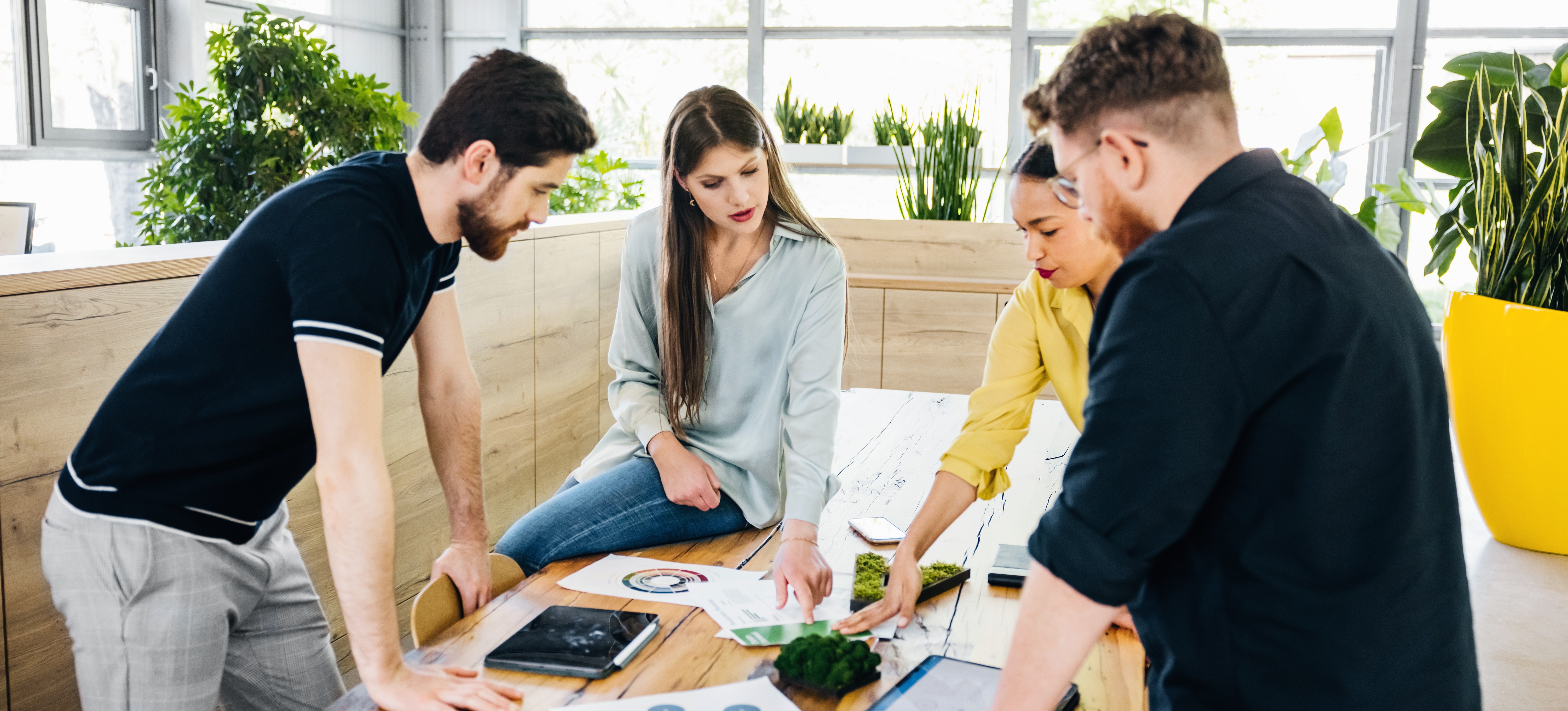[Featured Image] A product development engineer shows an array of product samples to three colleagues gathered around her in an office space.
