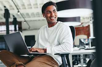 [Featured Image] A man works on a laptop computer in an office.