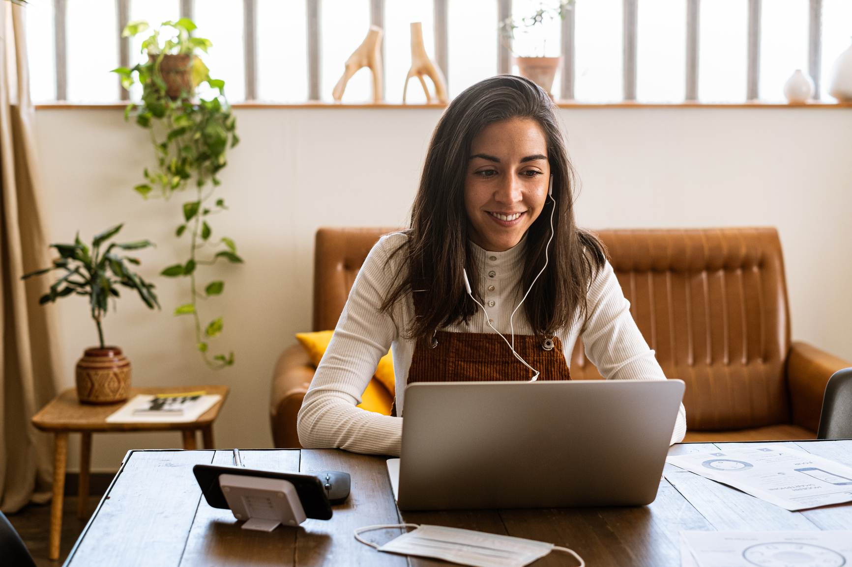 [Featured image] A woman wearing headphones listens to a webinar on her laptop to improve her writing skills.