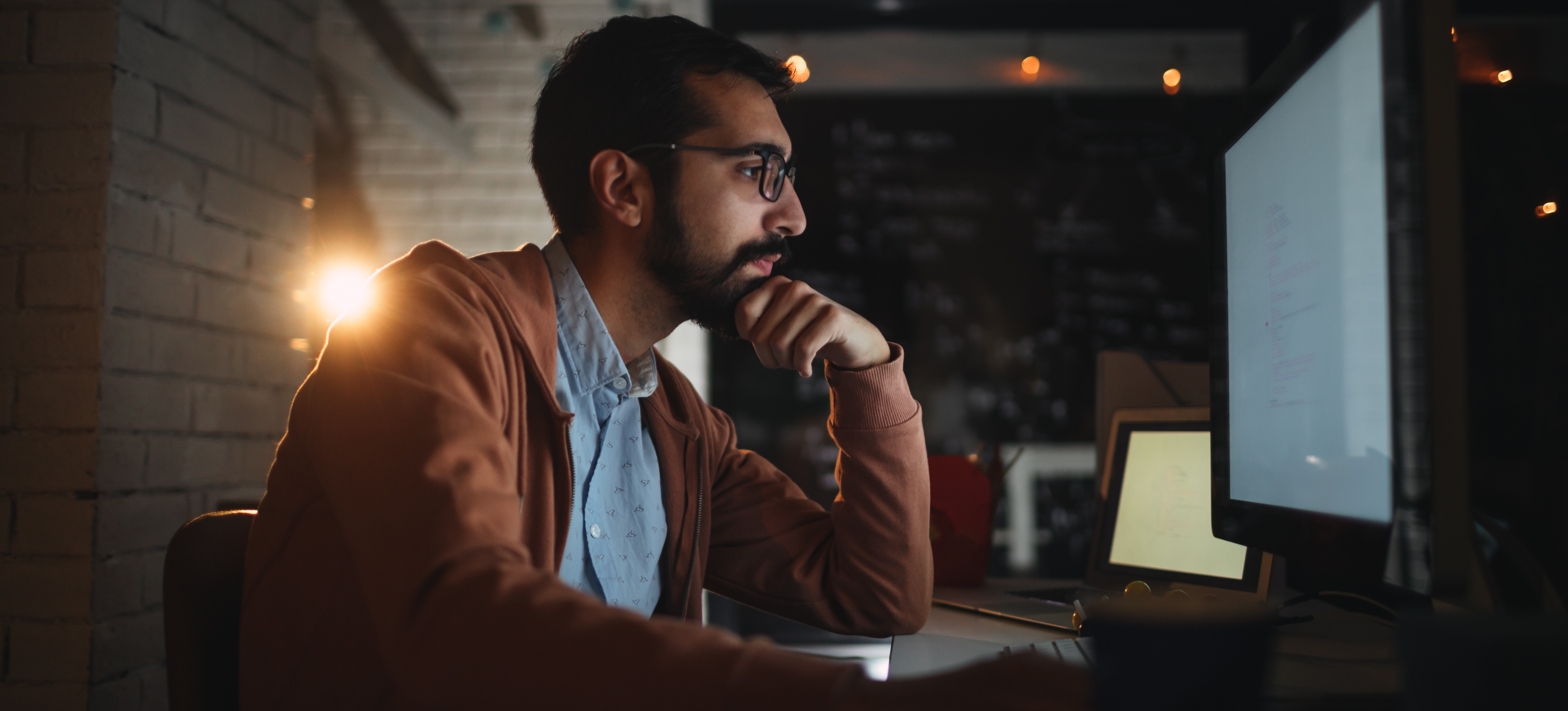 [Feature Image] A male graphic designer on a home office computer uses negative space in a new project.