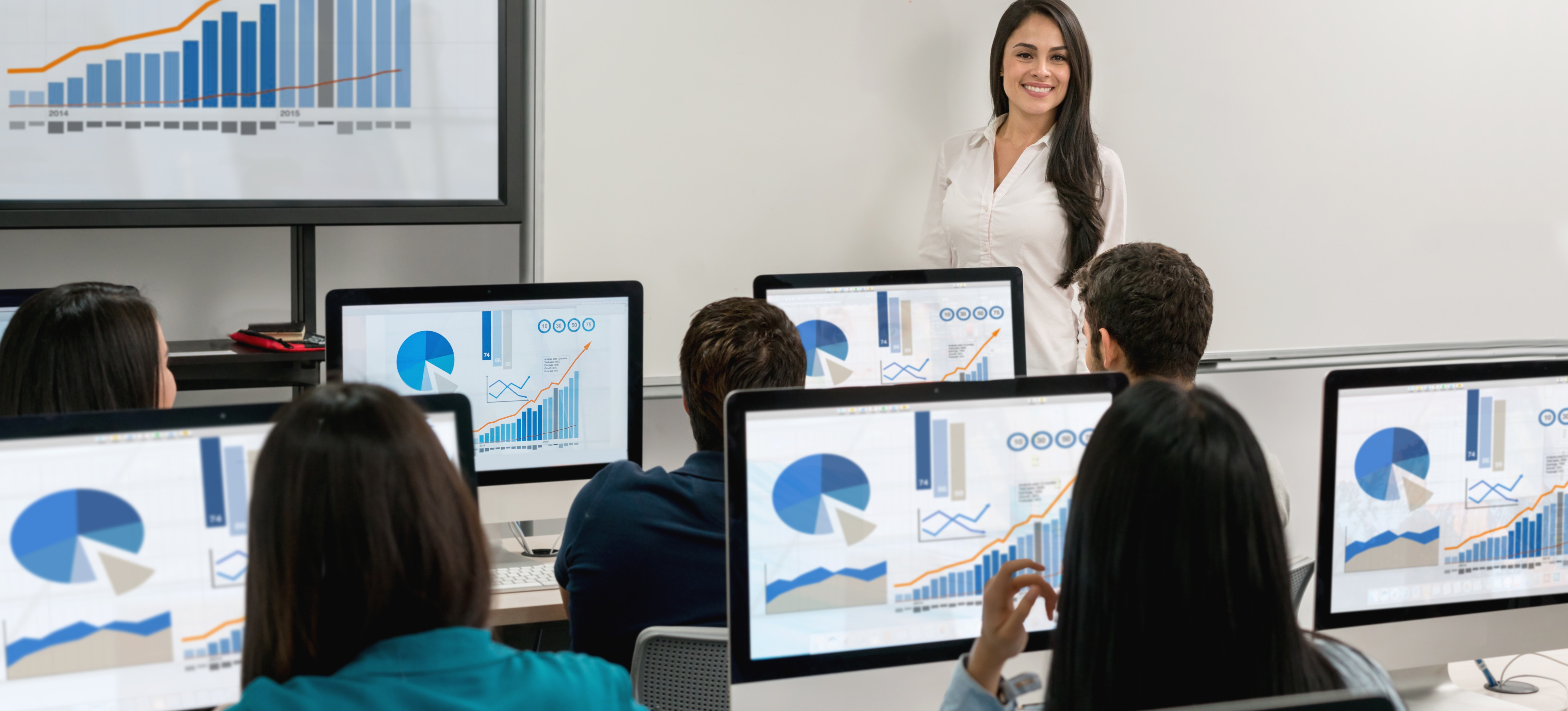 [Featured Image] A university professor teaching learners in a computer lab, with multiple screens displaying graphical data related to MATLAB studies.

