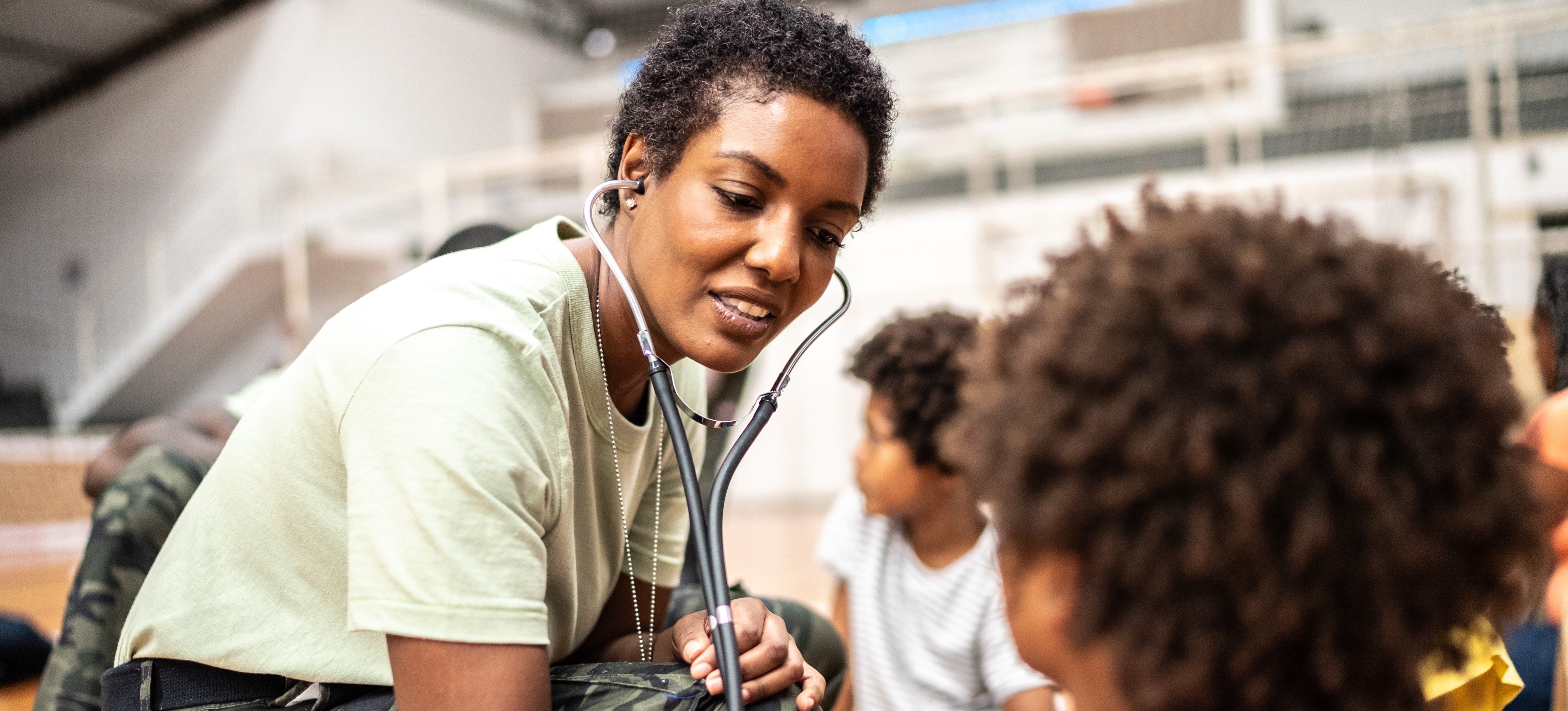[Featured Image] A military internist, one of the highest-paying military jobs, uses a stethoscope to examine young patients.
