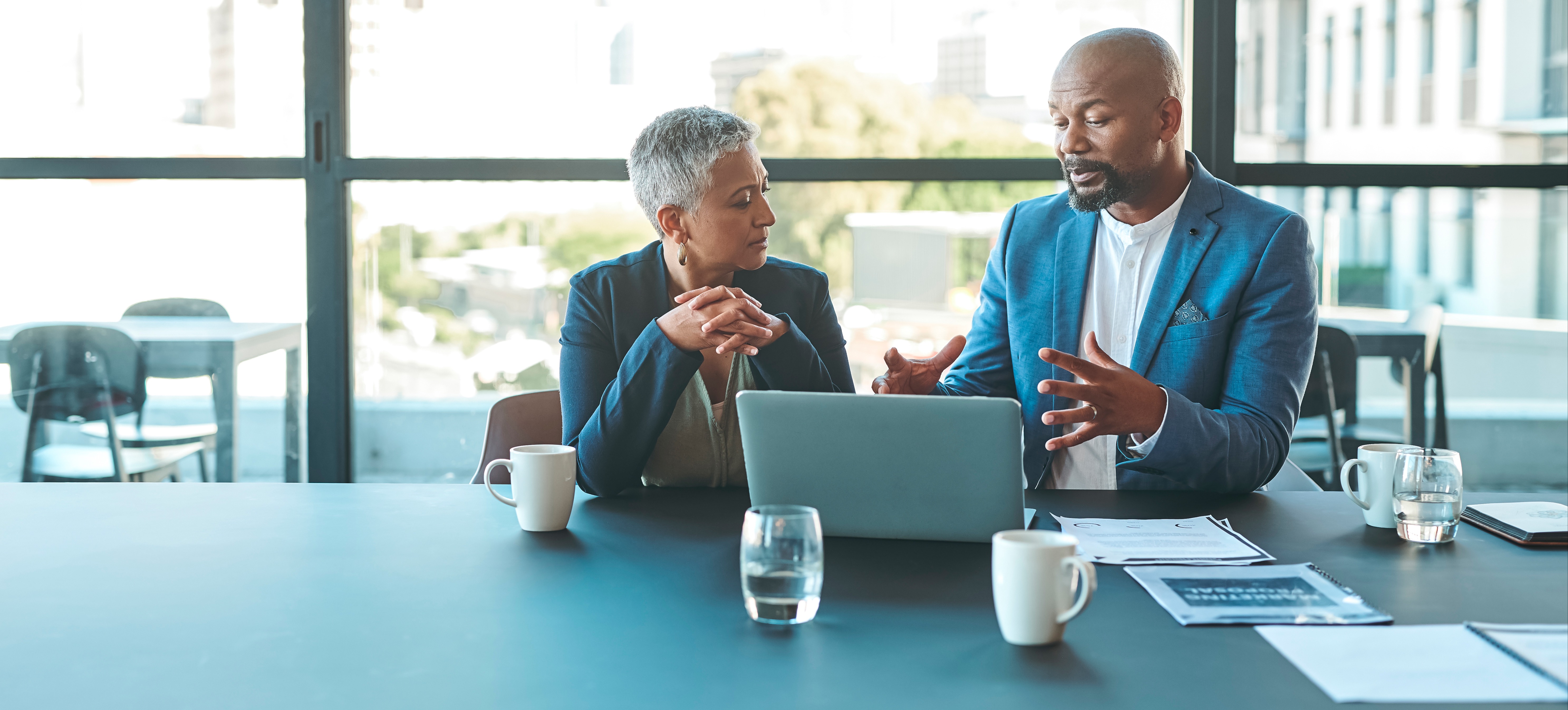 [Featured Image]: Two executives discuss how to implement machine learning into their business to improve decision-making.
