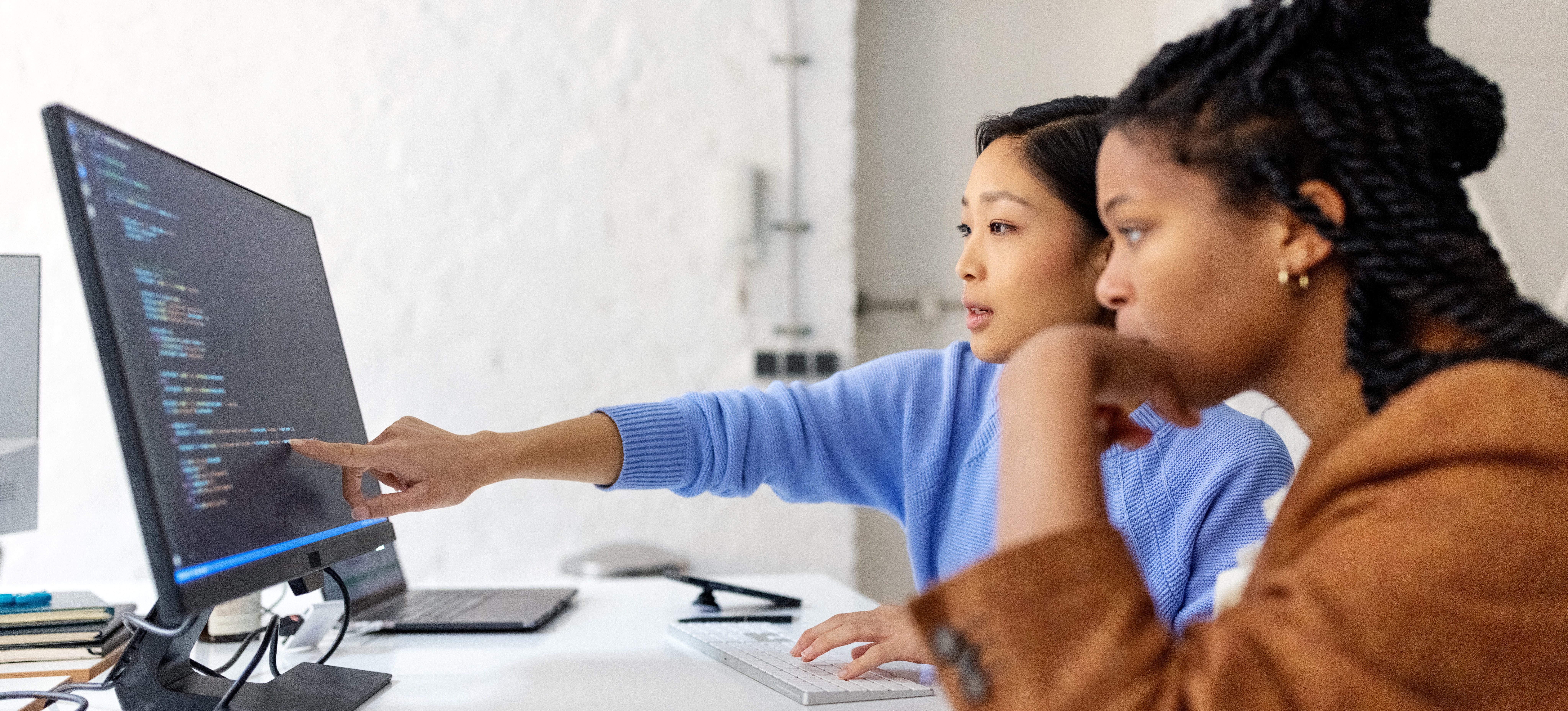 [Featured Image] Developers collaborating in front of a computer screen filled with code, discussing how natural language processing works.
