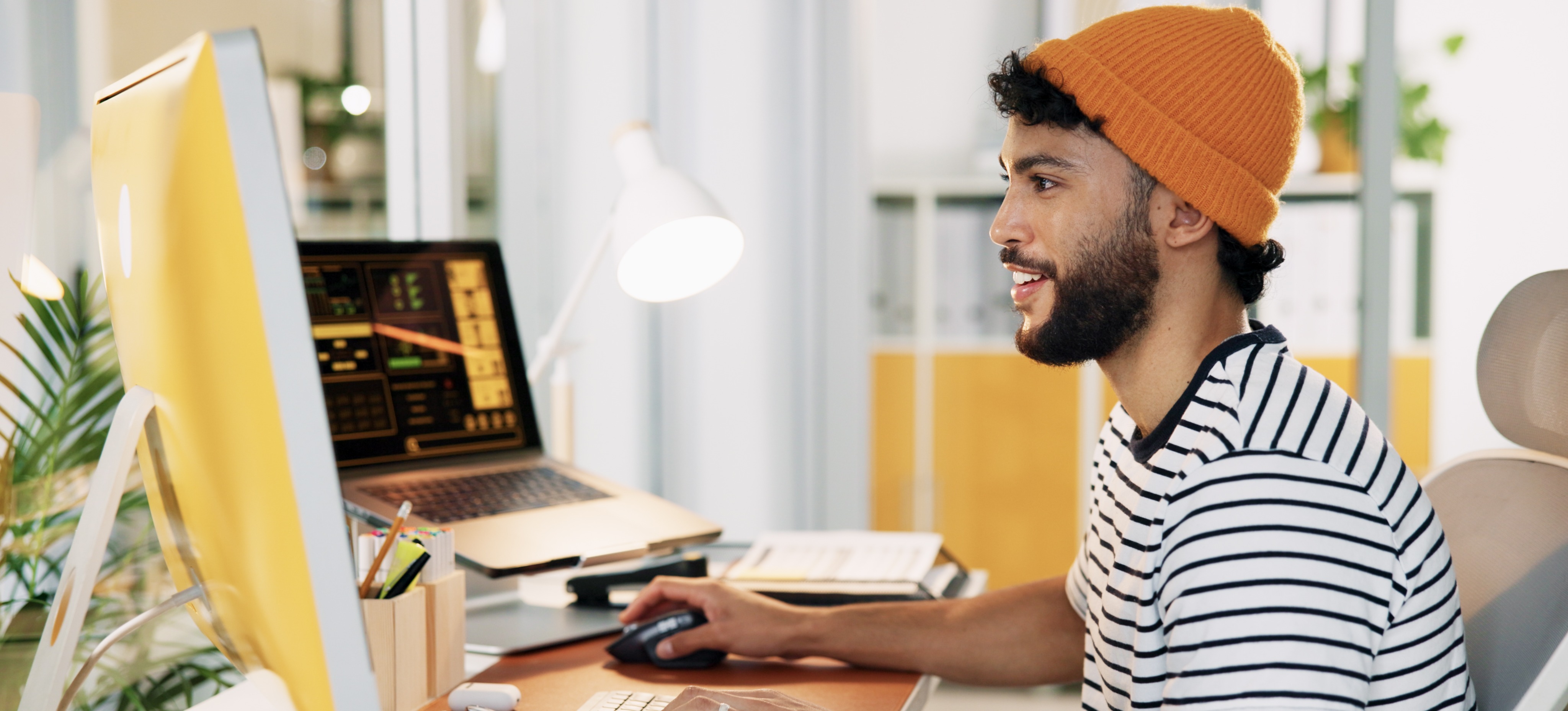 [Featured Image] A marketer works in a sunny office at their computer on generative engine optimization for their content marketing plan.
