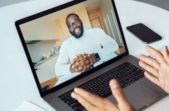 [Featured image] A person in a blue shirt and wearing AirPods uses their laptop to discuss cybersecurity interview questions on a video call. 