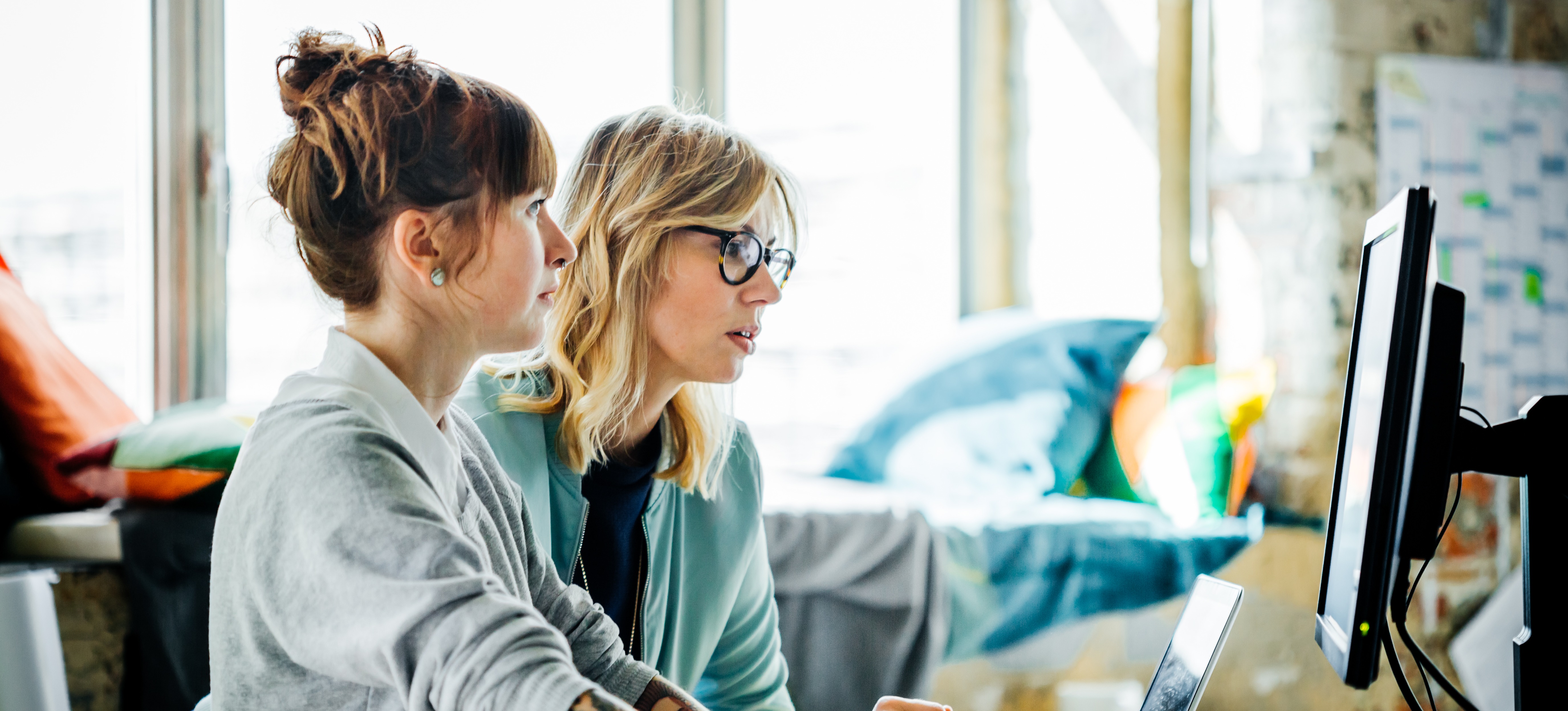 [Featured Image] Two business persons are in the office on a computer working on data segmentation to help their company.
