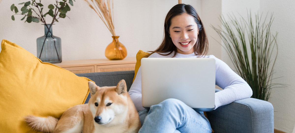 [Feature Image] A learner sits on a sofa next to their dog while researching “What is a recurrent neural network" on their laptop.
